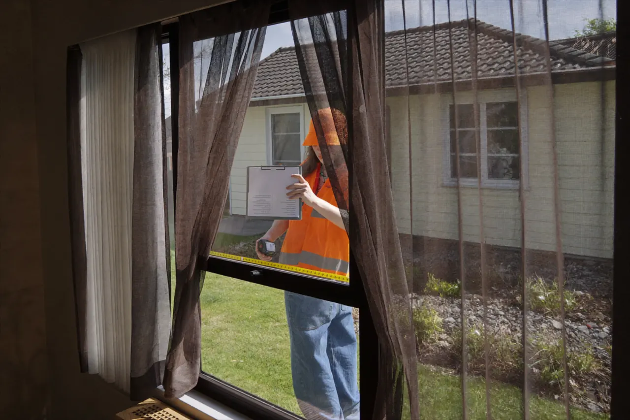 An installer fitting a sealed glass unit into a window frame