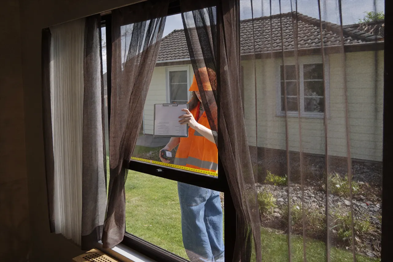 A surveyor measuring a window opening during a home visit